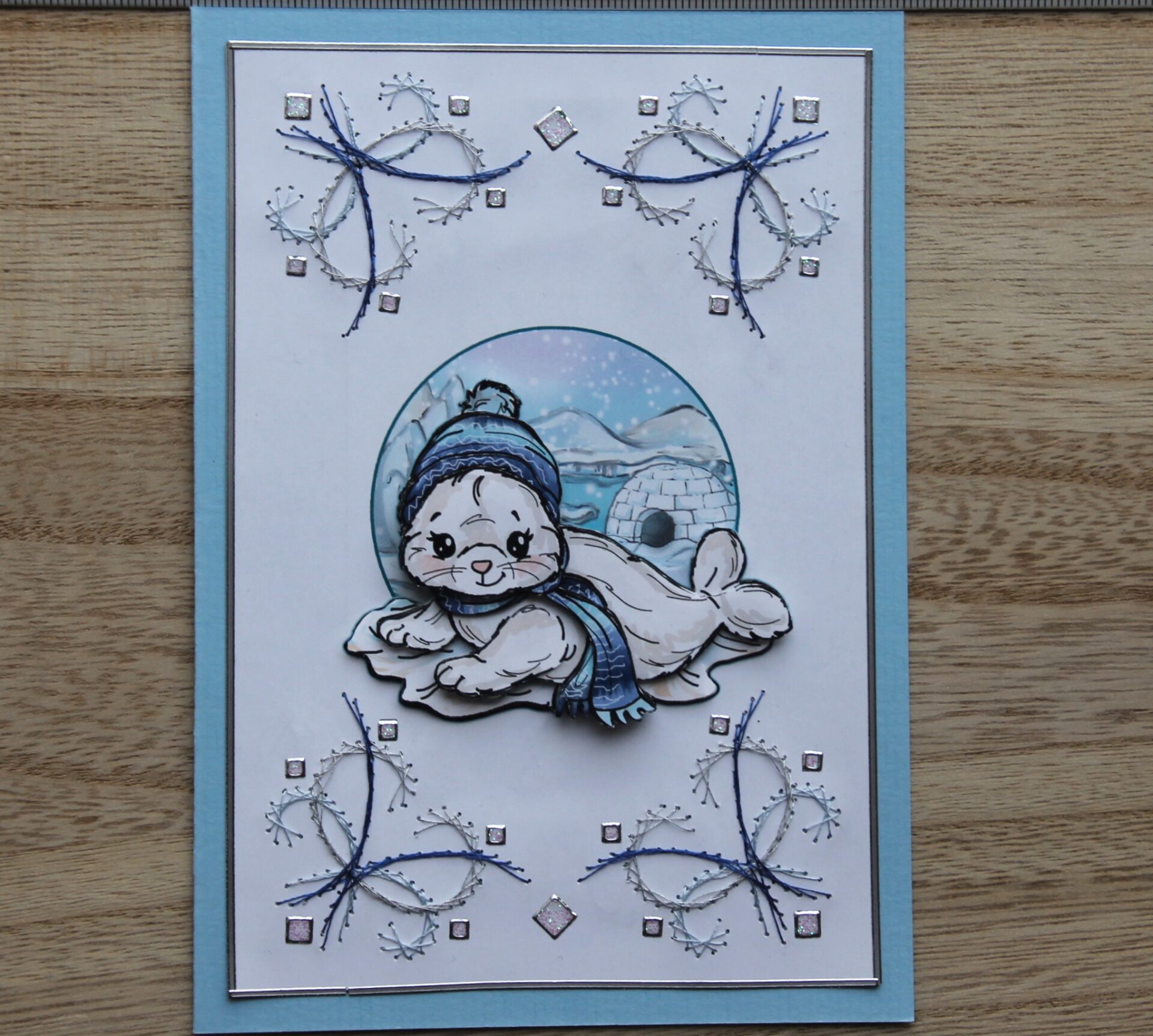 Borduurkaart blauw/wit, 3D-afbeelding zeehondje met muts en sjaal voor iglo